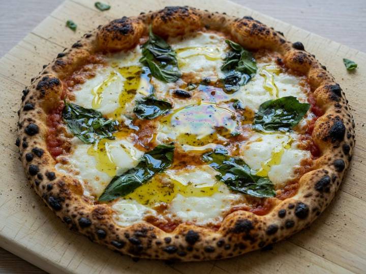 Margherita pizza finished with puddles of extra virgin olive oil and basil