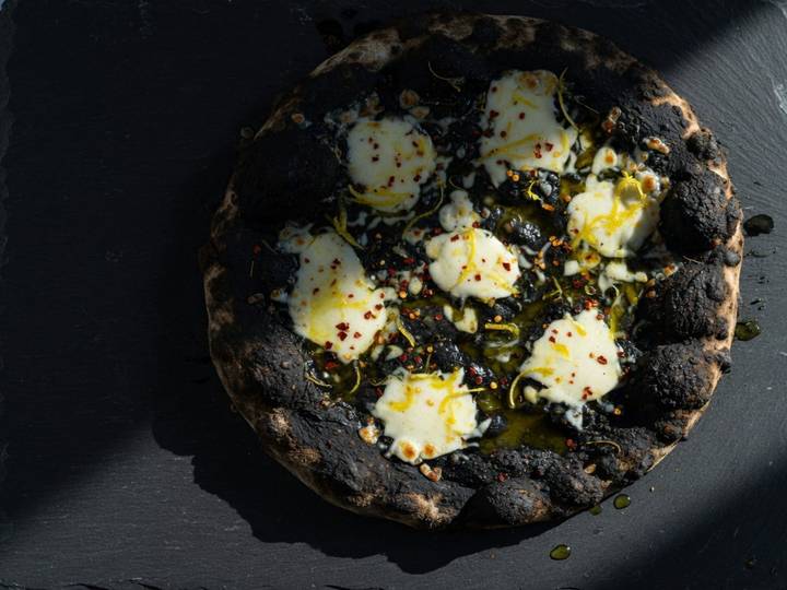 Black squid-ink pizza with mozzarella pools, chili flakes and lemon zest